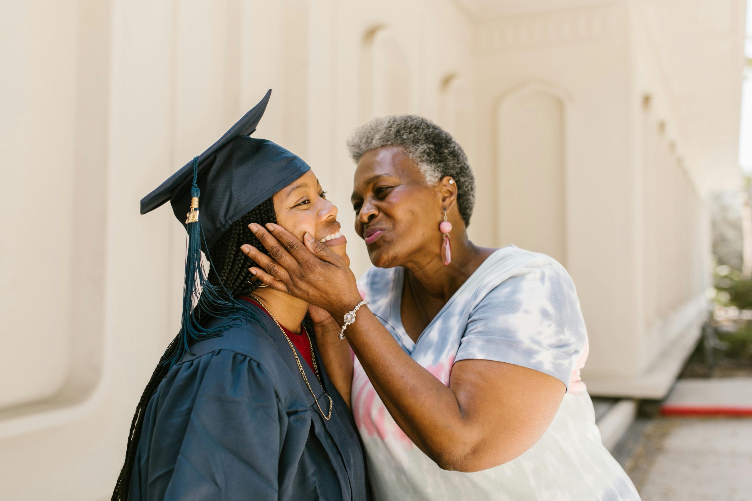 A touching moment between mother and daughter celebrating graduation outdoors.
