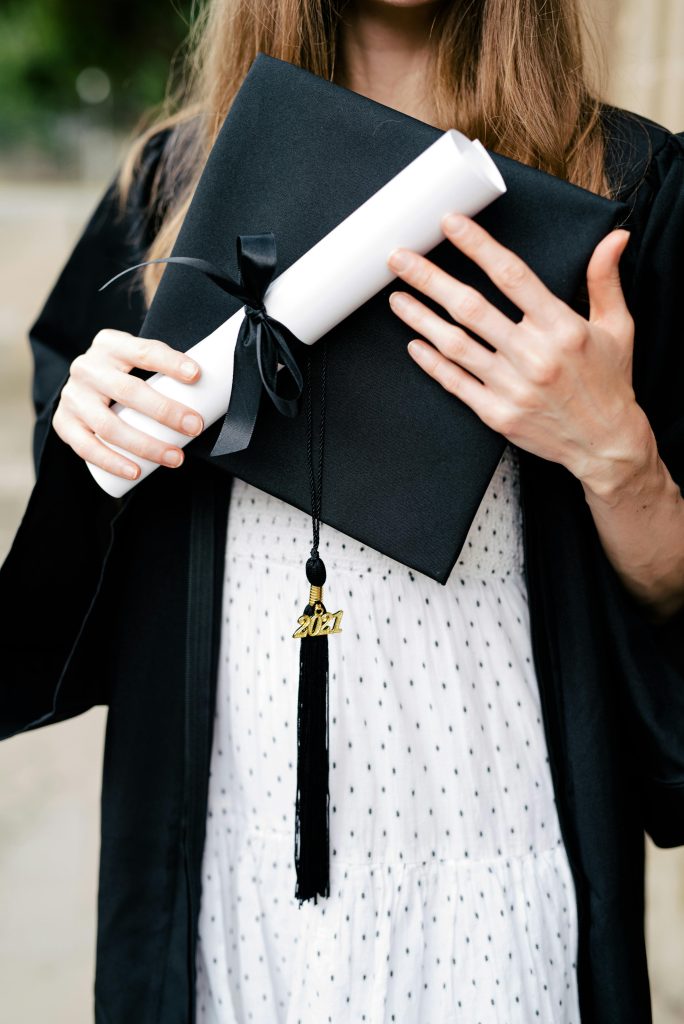 Close-up of a graduate holding a diploma and cap, symbolizing achievement.